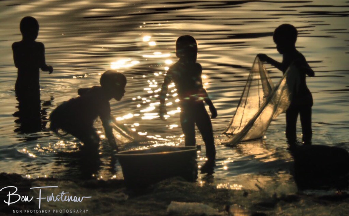 Sun reflections on kids net fishing in Chembe, Cape Maclear, Lake Malawi, Malawi