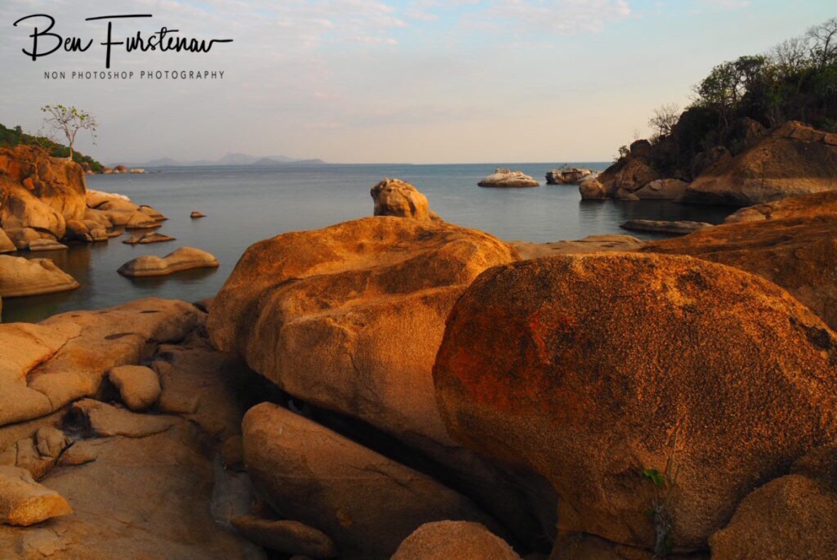 Calm waters over boulder shoreline looking south on Lake Malawi, Otter Point, Malawi 