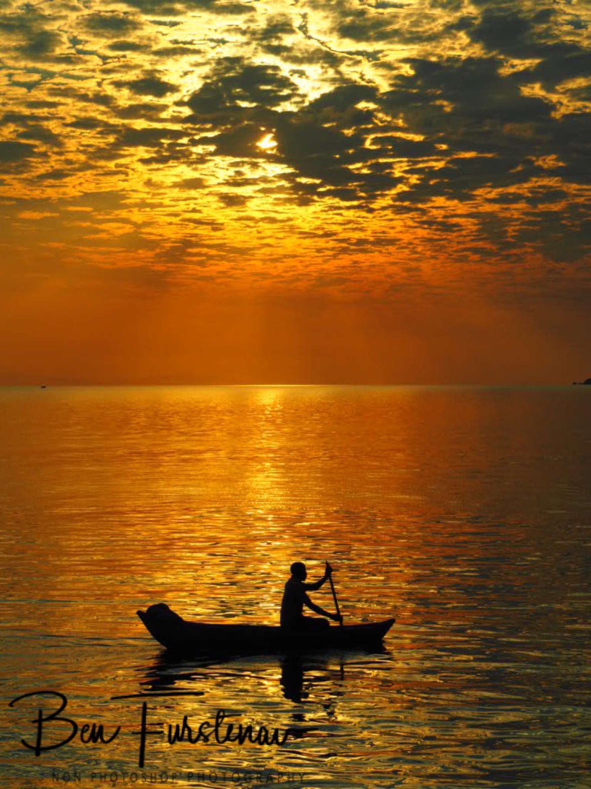 Banana boat fisherman in fiery red waters at Otter Point, Cape MaClear, Lake Malawi, Malawi 