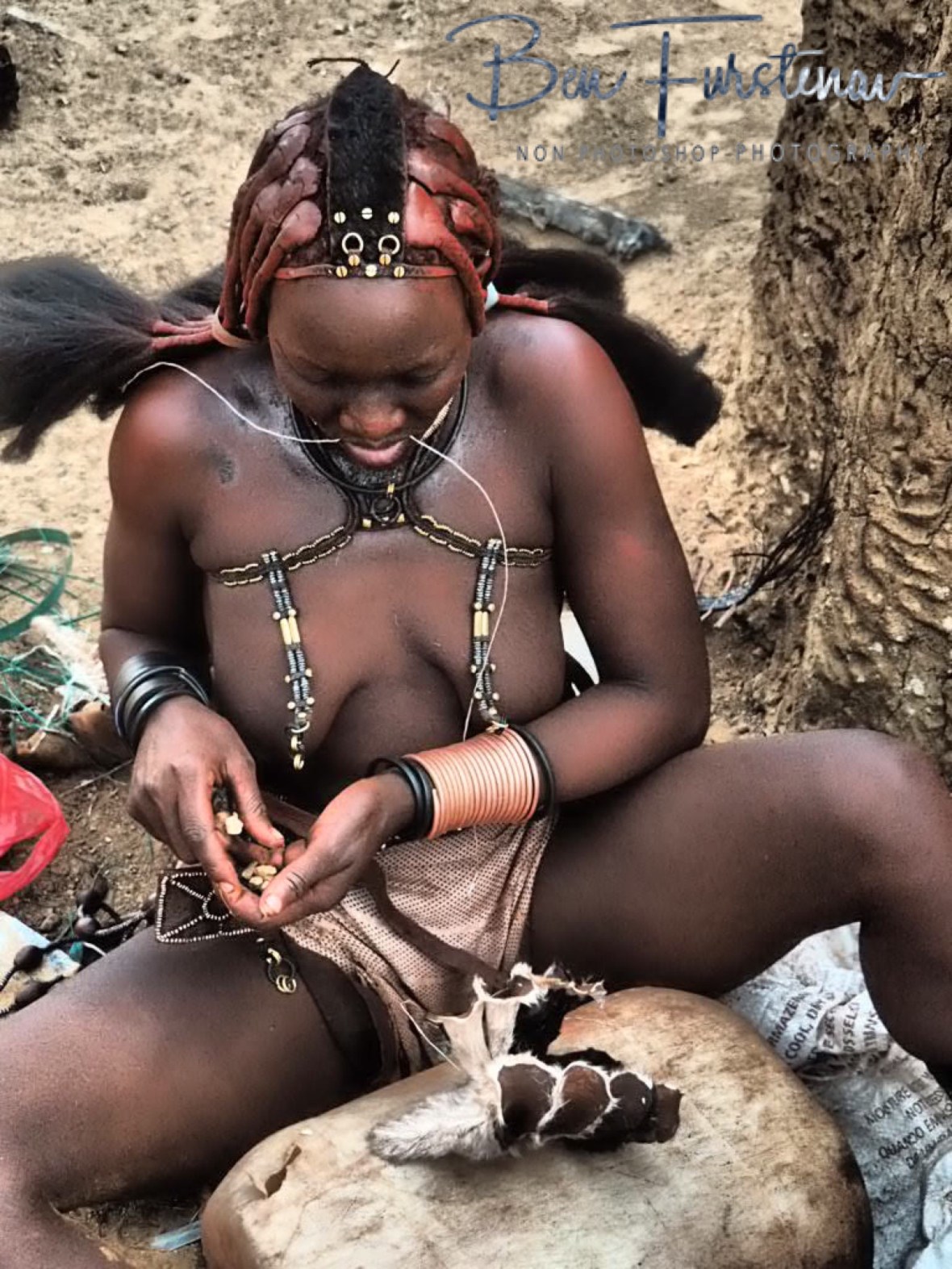 Placing stones to the hat to give it the horn shape, Omusaona Himba Village, Kamanjab, Namibia